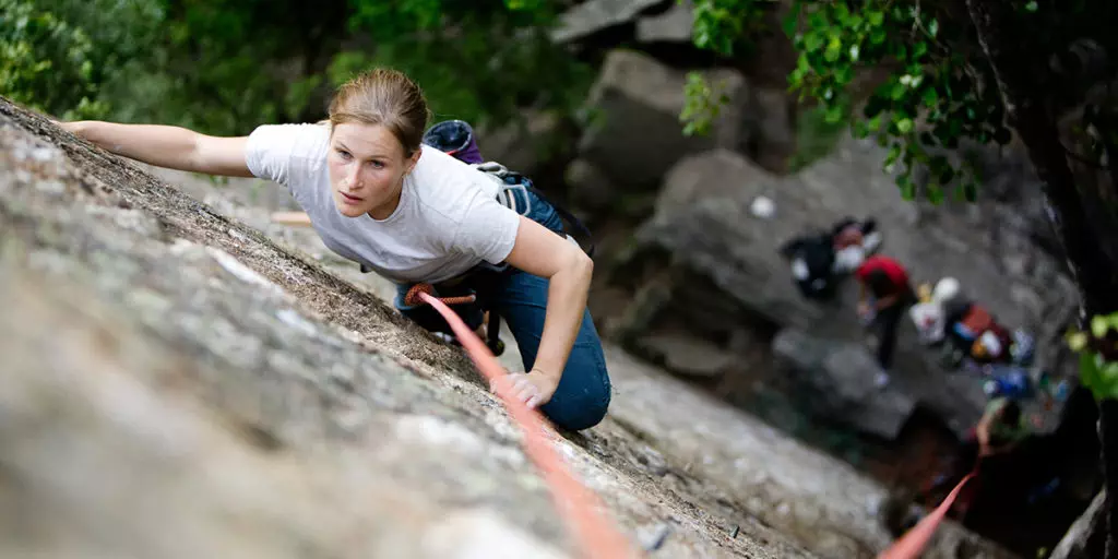 woman scaling a rock wall